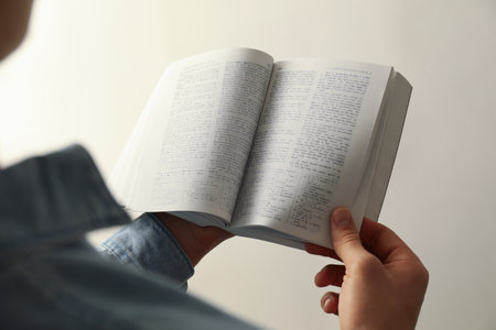 Man reading Holy Bible in English language on light background, closeupの写真素材