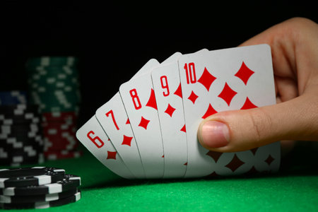 Woman with playing cards and poker chips at green table, closeup