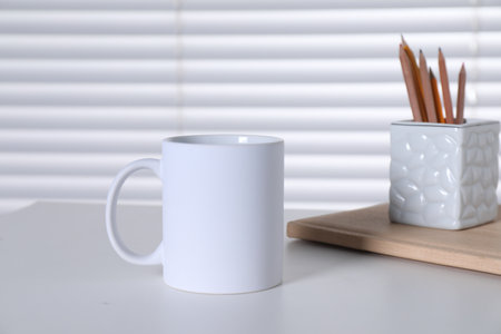 One blank ceramic mug and stationery on white table. Mockup for designの写真素材