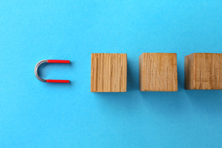 Magnet attracting wooden cubes on light blue background, flat layの写真素材