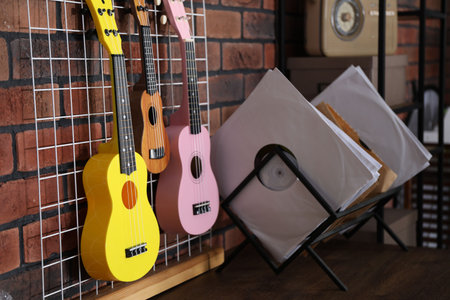 Three colorful ukulele on brick wall and records indoorsの写真素材