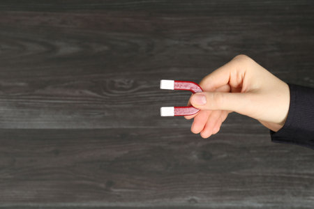 Woman with horseshoe magnet on wooden background, closeup. Space for textの写真素材