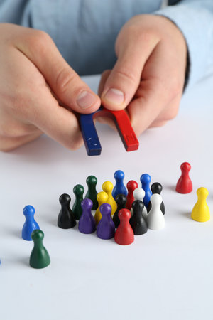 Man with magnet attracting game pieces at white table, closeupの写真素材