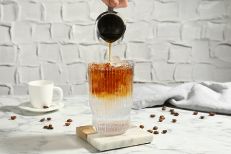 Woman making refreshing espresso tonic drink at white marble table, closeupの写真素材