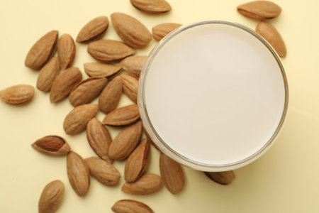 Fresh nut milk in glass and almonds on beige table, top viewの写真素材