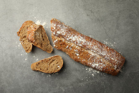 Cut fresh baguette on gray table, flat lay