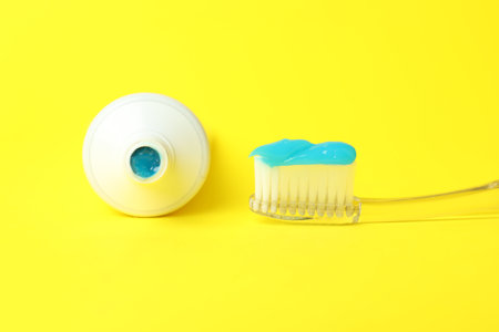 Toothbrush with toothpaste and tube on yellow background, closeupの写真素材