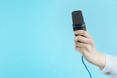 Woman with microphone on light blue background, closeup. Space for textの写真素材