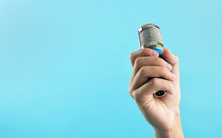 Man with microphone on light blue background, closeup. Space for textの写真素材