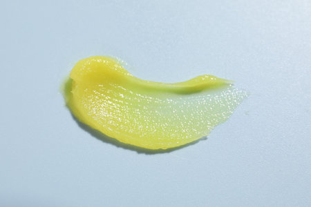 Sample of cosmetic product on light blue background, closeup