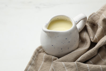 Condensed milk in jug on white marble table, closeupの写真素材