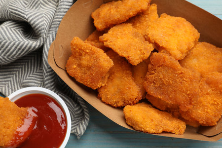 Delicious chicken nuggets with ketchup on blue wooden table, flat layの写真素材