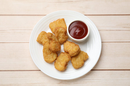 Delicious chicken nuggets and ketchup on wooden table, top viewの写真素材