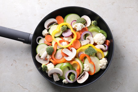 Frying pan with mix of vegetables and mushrooms on light gray table, top viewの写真素材