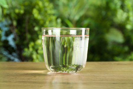 Glass of soda water on wooden table against blurred background