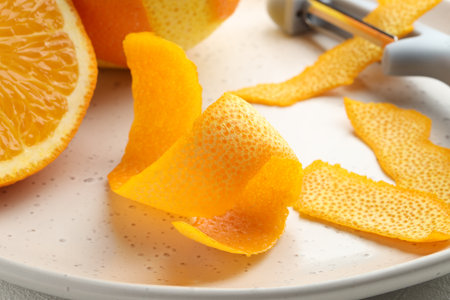 Fresh orange peel, fruit and peeler on table, closeupの写真素材