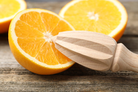 Juicer and fresh oranges on wooden table, closeupの写真素材