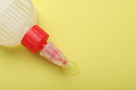 Bottle of glue on yellow background, top view. Space for textの写真素材