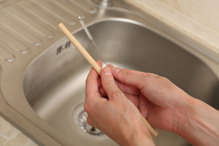 Woman cleaning bamboo drinking straw with brush in kitchen, closeupの写真素材