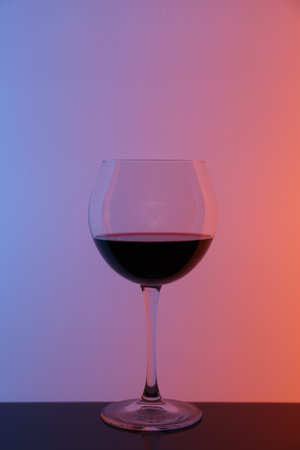 Glass of wine on table against color backgroundの写真素材