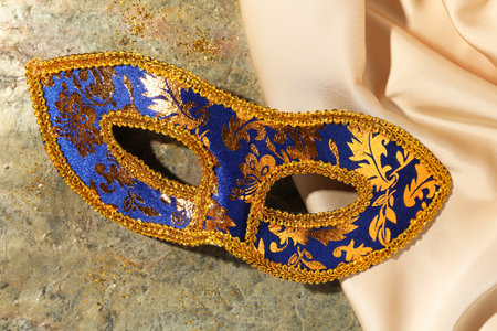 Beautiful bright carnival mask and beige fabric on gray textured table, top viewの写真素材