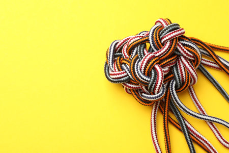 Braided colorful ropes on yellow background, top view with space for text. Unity concept