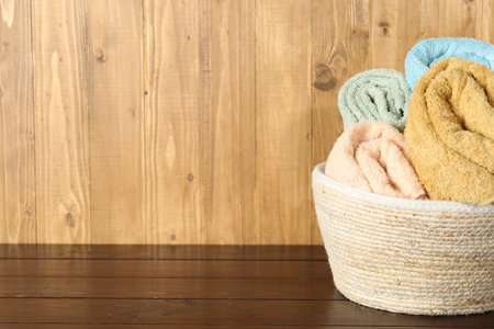 Wicker basket full of laundry on wooden table, space for textの写真素材