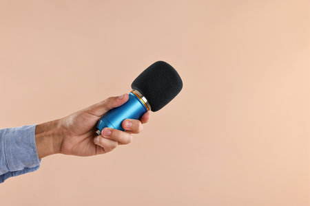 Man with microphone on beige background, closeupの写真素材