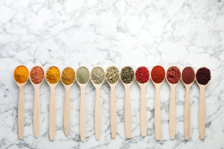 Different aromatic spices in spoons on white marble table, flat lay. Space for textの写真素材