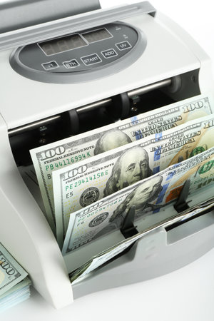 Money counter machine and dollar banknotes on white background, above viewの写真素材