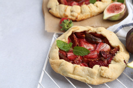 Tasty galettes with strawberries, figs and mint on light table, closeup. Space for textの写真素材