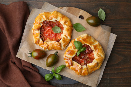 Tasty galettes with tomato and basil on wooden table, flat layの写真素材