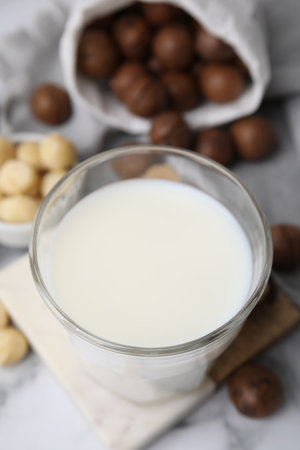 Glass of macadamia milk and nuts on white marble table, closeupの写真素材