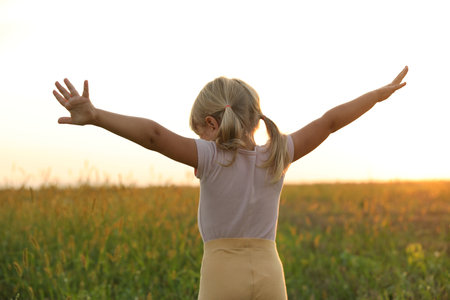 Cute little girl at meadow, back view. Child enjoying beautiful natureの写真素材