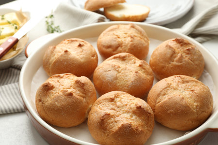 Baking dish with homemade tasty buns on light table, closeup