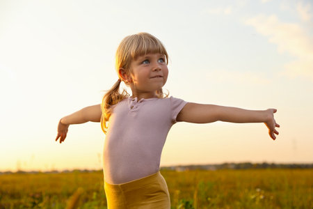 Cute little girl at meadow. Child enjoying beautiful natureの写真素材