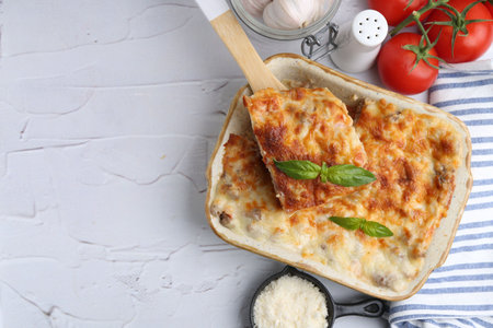 Delicious cooked lasagna with basil served on white textured table, flat lay. Space for textの写真素材