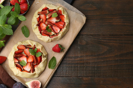 Uncooked galettes with strawberries and figs on wooden table, flat lay. Space for textの写真素材