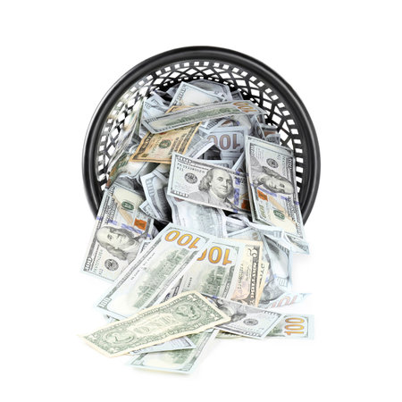 Many dollar banknotes and overturned trash bin isolated on whiteの写真素材