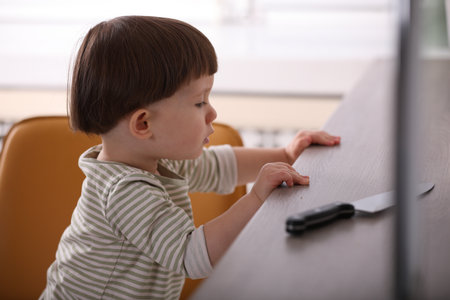 Little boy reaching towards knife on kitchen counter. Dangerous situationの写真素材