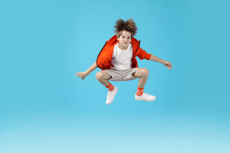 Happy little boy jumping on light blue background