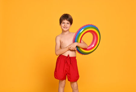 Happy little boy with inflatable ring on orange backgroundの写真素材