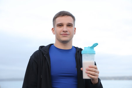 Person in athletic wear holding a fitness shaker outdoors