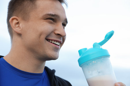Person with shaker of protein drink outdoors, closeupの写真素材