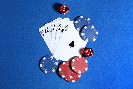 Playing cards, poker chips and cubes on blue table, flat lay