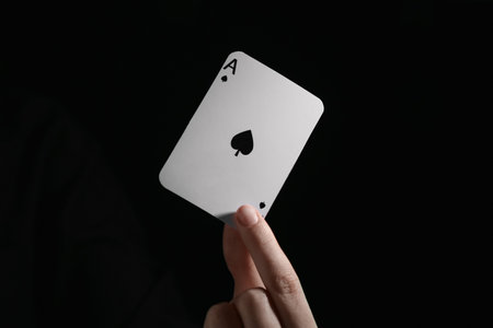 Woman with playing card against black background, closeupの写真素材