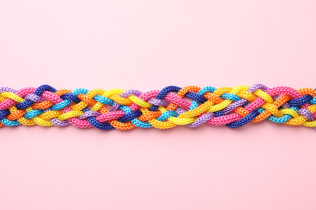 Braided colorful ropes on pink background, top view. Unity conceptの写真素材