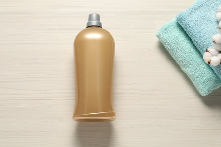 Bottle with clean towels and cotton flowers on wooden background, flat layの写真素材