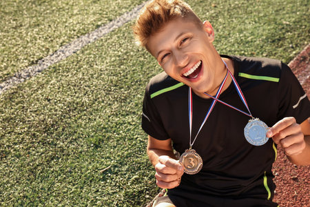 Happy winner with different medals sitting at stadium on sunny day. Space for textの写真素材