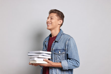 Happy student with stack of books on gray backgroundの写真素材